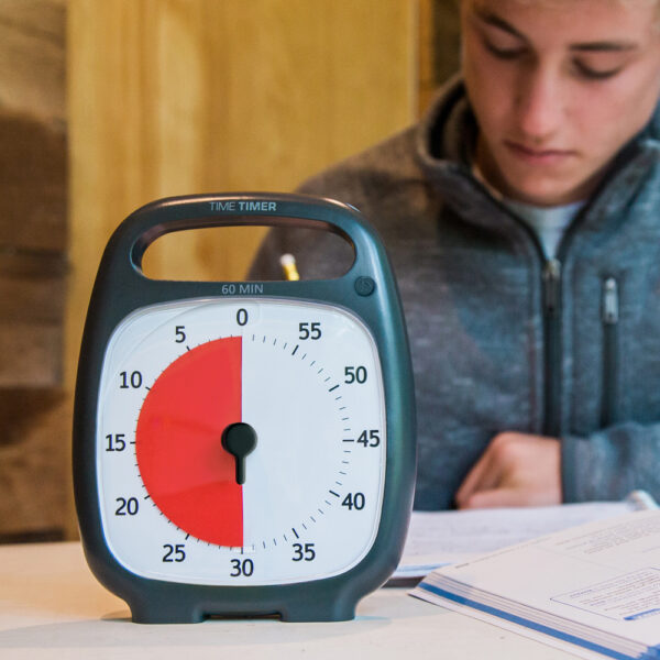 Time Timer Plus med kille i bakgrunden som gör läxor